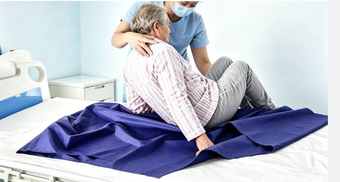Cuidadora a movimentar um doente na cama com o Lençol Ultra Deslizante